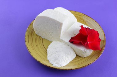 Peynir ve yaprakları kırmızı gül, mor bir arka plan üzerinde Yunan peynir, beyaz peynir süt ürünleri tarzında bir minimalizm, sarı bir tabakta kopyalama alanı, Festival gıda, süt Kahvaltı, ultraviyole