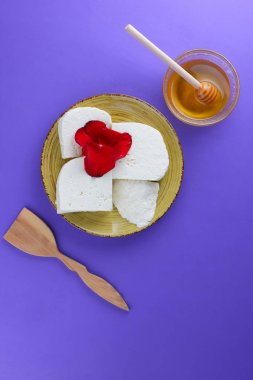 Peynir ve bal, yaprakları kırmızı gül, Yunan peynir bir mor arka plan, sarı bir plaka üzerinde beyaz peynir, minimalizm, tarzında süt ürünleri kopyalama alanı, Festival gıda, süt Kahvaltı, ultraviyole, tatlım