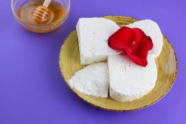 Peynir ve bal, yaprakları kırmızı gül, Yunan peynir bir mor arka plan, sarı bir plaka üzerinde beyaz peynir, minimalizm, tarzında süt ürünleri kopyalama alanı, Festival gıda, süt Kahvaltı, ultraviyole, tatlım