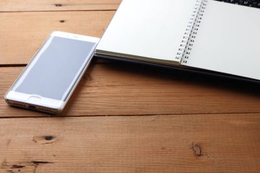 Bir dizüstü bilgisayar ve bir fincan kahve ahşap arka plan üzerinde bir iş istasyonu üzerinde eski bir Resepsiyon, bir smartphone ve bir defter, kalem ve gözlük işyeri, alan bir kopyasını, minimalist tarzı tasarımcı bir iş istasyonu
