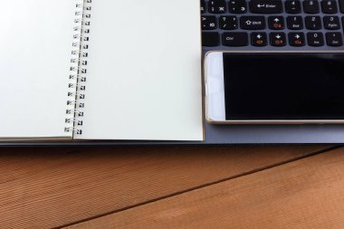 Bir dizüstü bilgisayar ve bir fincan kahve ahşap arka plan üzerinde bir iş istasyonu üzerinde eski bir Resepsiyon, bir smartphone ve bir defter, kalem ve gözlük işyeri, alan bir kopyasını, minimalist tarzı tasarımcı bir iş istasyonu