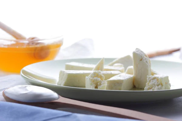 チーズ 蜂蜜とサワー クリーム 白い背景 サワー クリーム フレンチ ブレックファースト 青いナプキン 木のスプーンの柔らかいチーズ — ストック写真