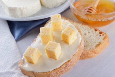 Peynir ve bal bir beyaz tabak, kefir ve yumuşak peynir, minimalizm, bal ve bir parça ekmek mavi gelmedi sandviçle, Fransız beyaz bir arka plan üzerinde Amerikan mutfağı Servis Kahvaltı