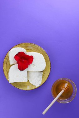 Peynir ve bal, yaprakları kırmızı gül, Yunan peynir bir mor arka plan, sarı bir plaka üzerinde beyaz peynir, minimalizm, tarzında süt ürünleri kopyalama alanı, süt Kahvaltı, ultraviyole, tatlım, sanat