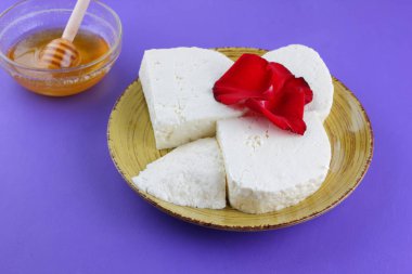 Peynir ve bal, yaprakları kırmızı gül, Yunan peynir bir mor arka plan, sarı bir plaka üzerinde beyaz peynir, minimalizm, tarzında süt ürünleri kopyalama alanı, süt Kahvaltı, ultraviyole, tatlım, sanat