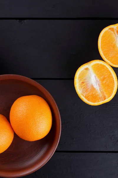 Oranges in a wooden box on a black background, citrus in retro style, copy space, orange fruits on a wooden background, tropical fruits in a box on a table, half orange for a vegan