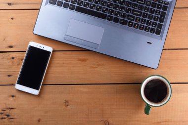 Kahve ahşap arka plan üzerinde eski bir Resepsiyon, smartphone ve bir dizüstü bilgisayar, iş istasyonunda bir dizüstü bilgisayar ve kalem ve işyeri, tasarımcı iş istasyonu, sanat gözlük