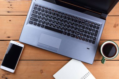 Kahve ahşap arka plan üzerinde eski bir Resepsiyon, smartphone ve bir dizüstü bilgisayar, iş istasyonunda bir dizüstü bilgisayar ve kalem ve işyeri, tasarımcı iş istasyonu, sanat gözlük