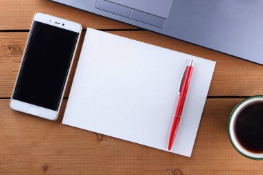 Kahve ahşap arka plan üzerinde eski bir Resepsiyon, smartphone ve bir dizüstü bilgisayar, iş istasyonunda bir dizüstü bilgisayar ve kalem ve işyeri, tasarımcı iş istasyonu, office gözlük