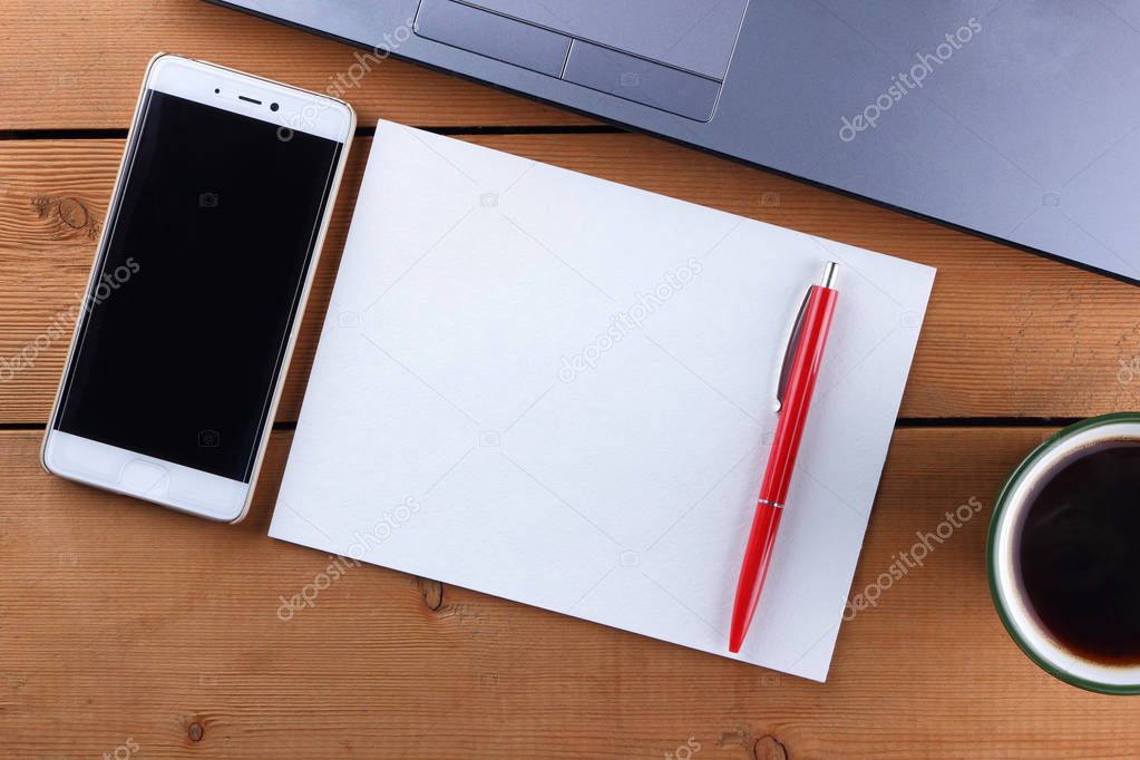Laptop and cup of coffee on a wooden background, workstation on an old desk, smartphone and a notebook, pen and glasses in the workplace, designer workstation, office