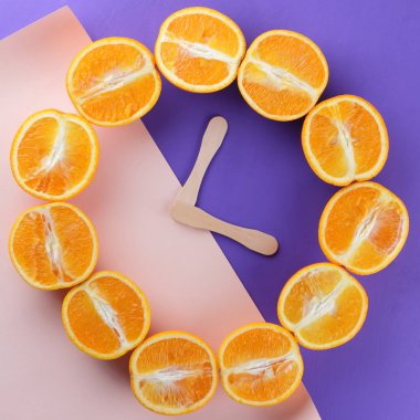 Meyve Portakal, portakal mor bir arka planda bir ultraviyole arka planda, ahşap saat eller, narenciye daireye yarısı yaratıcı yapılan saat, pop art, bir tasarımcı için boş