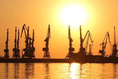 Seaport gün batımında, Vinç ufukta turuncu gökyüzü deniz ufuk, yatay, yüksek katlı Vinçler, deniz bir Dalgakıran inşaatı karşı limanda