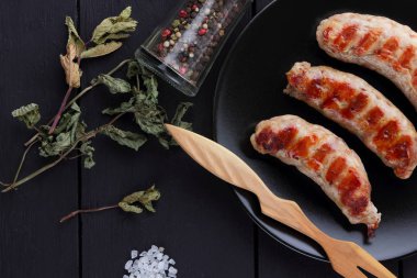 Ev ızgara sosis bir siyah plaka, koyu ahşap arka plan, sıcak sosis baharatlar ile bir et yemeği ve ev bir mutfak, kopya alanı, rustik tarzı tuz