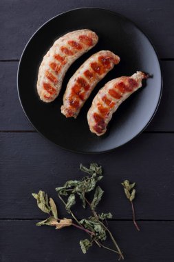 Ev ızgara sosis bir siyah plaka, koyu ahşap arka plan, sıcak sosis baharatlar ile bir et yemeği ve ev bir mutfak, kopya alanı, rustik tarzı tuz