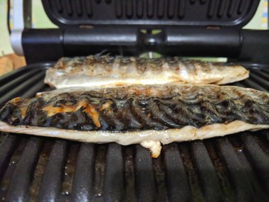 Uskumru üzerinde pişmiş ızgara, altın pişmiş kabuk, ev yapımı yemekler, siyah ızgara yüzeyi, Asya mutfağı, tatil tablo, retro tarzı yiyecek kızarmış balık ile balık