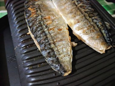 Uskumru üzerinde pişmiş ızgara, altın pişmiş kabuk, ev yapımı yemekler, siyah ızgara yüzeyi, Asya mutfağı, tatil tablo, retro tarzı yiyecek kızarmış balık ile balık
