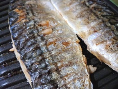 Uskumru üzerinde pişmiş ızgara, altın pişmiş kabuk, ev yapımı yemekler, siyah ızgara yüzeyi, Asya mutfağı, tatil tablo, retro tarzı yiyecek kızarmış balık ile balık
