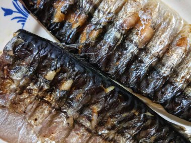 Uskumru üzerinde pişmiş ızgara, altın pişmiş kabuk, ev yapımı yemekler, siyah ızgara yüzeyi, Asya mutfağı, tatil tablo, retro tarzı yiyecek kızarmış balık ile balık