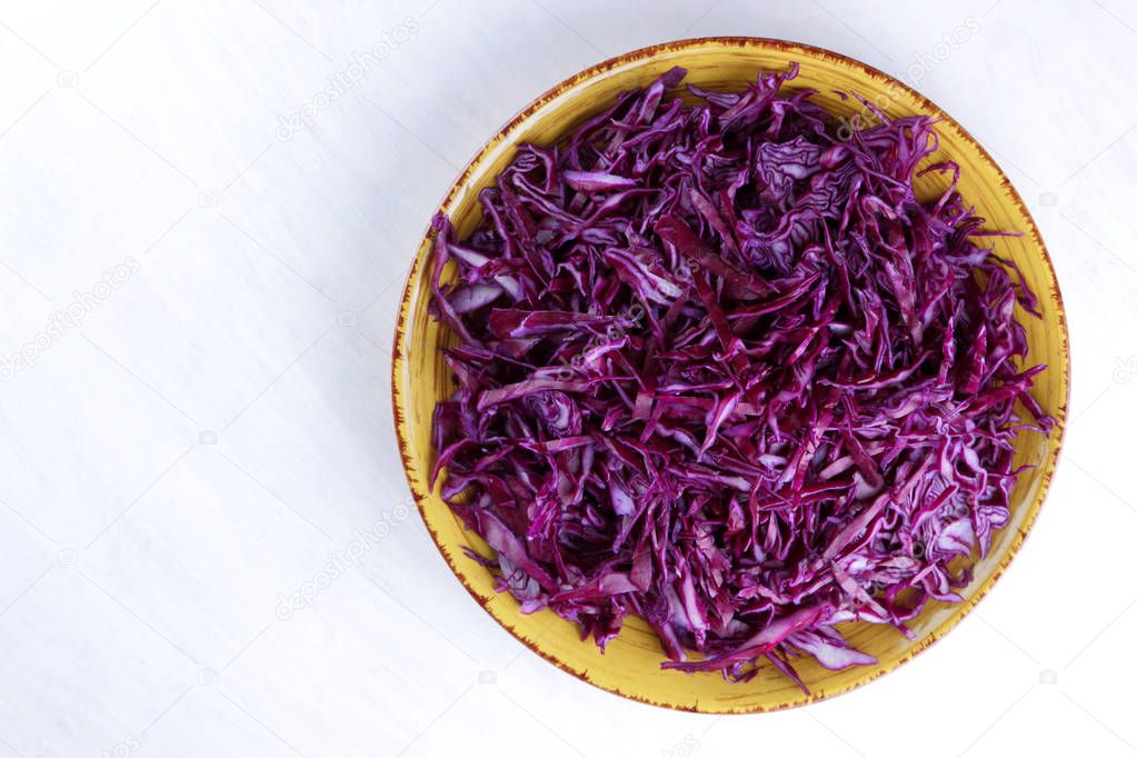Chopped cabbage on white background, red cabbage on a yellow plate, copy space, top view, vegetarian food, fresh vegetables for salad, white background, minimalism, isolated