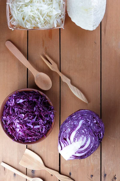 Assorted cabbage, chopped red cabbage and cabbage on a wooden background, vegetables in a clay bowl, a wooden box with vegetables, vegetarian food, wooden cutlery