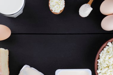 Yumuşak peynir ve yumurta karanlık panoları, bir bardak süt, bir kil plaka, ahşap çatal bıçak takımı, rustik tarzı, süzme peynir süt ürünleri çeşitli karanlık bir arka plan üzerinde kopyalama alanı, ekmek