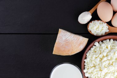 Süzme peynir ve yumurta karanlık bir arka planda çeşitli süt ürünleri karanlık panoları, bir bardak süt, bir kil plaka, ahşap çatal bıçak takımı, rustik tarzı, kopya alanı, yumuşak peynir ekmek