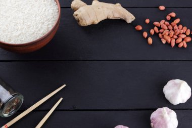 Çeşitli Asya vejetaryen yemek malzemeler. Kuruyemiş, sebze, zencefil kökü. Taze yeşillik, dereotu ve maydanoz. Pirinç, fıstık ve siyah bir zemin üzerine baharat. Uzay kopyalayın. Çin yemek çubukları