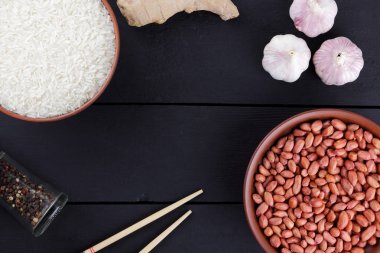 Çeşitli Asya vejetaryen yemek malzemeler. Kuruyemiş, sebze, zencefil kökü. Taze yeşillik, dereotu ve maydanoz. Pirinç, fıstık ve siyah bir zemin üzerine baharat. Uzay kopyalayın. Çin yemek çubukları