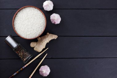 Çeşitli Asya vejetaryen yemek malzemeler. Kuruyemiş, sebze, zencefil kökü. Taze yeşillik, dereotu ve maydanoz. Pirinç, fıstık ve siyah bir zemin üzerine baharat. Uzay kopyalayın. Çin yemek çubukları