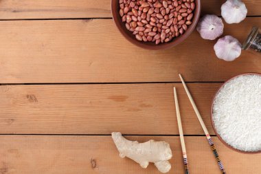 Çeşitli Asya vejetaryen yemek malzemeler. Kuruyemiş, sebze, zencefil kökü. Taze yeşillik, dereotu ve maydanoz. Pirinç, fıstık ve baharat ahşap arka plan üzerinde. Uzay kopyalayın. Çin yemek çubukları