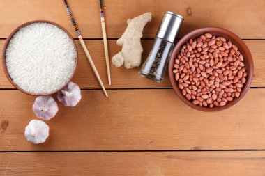 Çeşitli Asya vejetaryen yemek malzemeler. Kuruyemiş, sebze, zencefil kökü. Taze yeşillik, dereotu ve maydanoz. Pirinç, fıstık ve baharat ahşap arka plan üzerinde. Uzay kopyalayın. Çin yemek çubukları