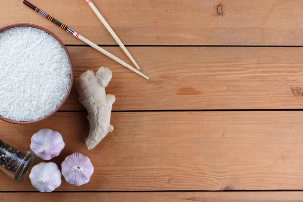 Çeşitli Asya vejetaryen yemek malzemeler. Kuruyemiş, sebze, zencefil kökü. Taze yeşillik, dereotu ve maydanoz. Pirinç, fıstık ve baharat ahşap arka plan üzerinde. Uzay kopyalayın. Çin yemek çubukları