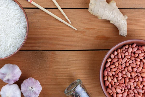 Çeşitli Asya vejetaryen yemek malzemeler. Kuruyemiş, sebze, zencefil kökü. Taze yeşillik, dereotu ve maydanoz. Pirinç, fıstık ve baharat ahşap arka plan üzerinde. Uzay kopyalayın. Çin yemek çubukları