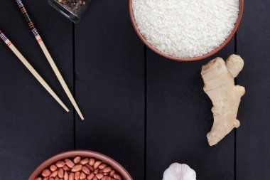 Çeşitli Asya vejetaryen yemek malzemeler. Kuruyemiş, sebze, zencefil kökü. Taze yeşillik, dereotu ve maydanoz. Pirinç, fıstık ve siyah bir zemin üzerine baharat. Uzay kopyalayın. Çin yemek çubukları. Sanat