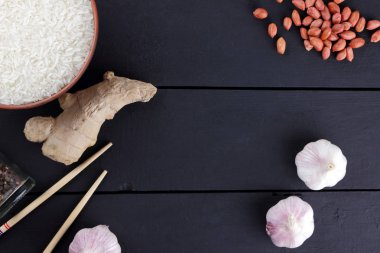 Çeşitli Asya vejetaryen yemek malzemeler. Kuruyemiş, sebze, zencefil kökü. Taze yeşillik, dereotu ve maydanoz. Pirinç, fıstık ve siyah bir zemin üzerine baharat. Uzay kopyalayın. Çin yemek çubukları. Sanat