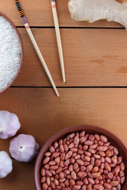 Çeşitli Asya vejetaryen yemek malzemeler. Kuruyemiş, sebze, zencefil kökü. Taze yeşillik, dereotu ve maydanoz. Pirinç, fıstık ve baharat ahşap arka plan üzerinde. Uzay kopyalayın. Çin yemek çubukları. Sanat