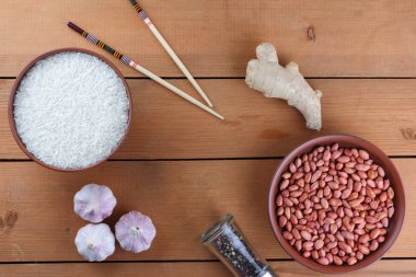 Çeşitli Asya vejetaryen yemek malzemeler. Kuruyemiş, sebze, zencefil kökü. Taze yeşillik, dereotu ve maydanoz. Pirinç, fıstık ve baharat ahşap arka plan üzerinde. Uzay kopyalayın. Çin yemek çubukları. Sanat