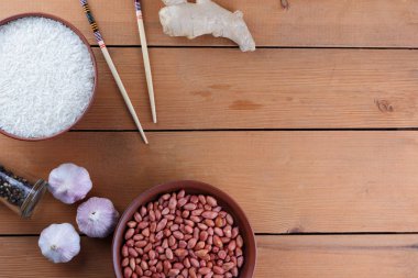 Çeşitli Asya vejetaryen yemek malzemeler. Kuruyemiş, sebze, zencefil kökü. Taze yeşillik, dereotu ve maydanoz. Pirinç, fıstık ve baharat ahşap arka plan üzerinde. Uzay kopyalayın. Çin yemek çubukları. Sanat