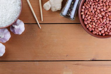 Çeşitli Asya vejetaryen yemek malzemeler. Kuruyemiş, sebze, zencefil kökü. Taze yeşillik, dereotu ve maydanoz. Pirinç, fıstık ve baharat ahşap arka plan üzerinde. Uzay kopyalayın. Çin yemek çubukları. Sanat