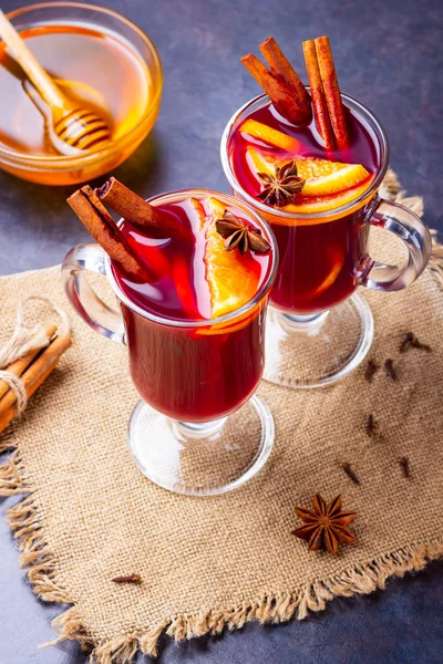 Red mulled wine on burlap. Mulled wine with oranges, cinnamon and cloves on a dark background. Hot wine with spices
