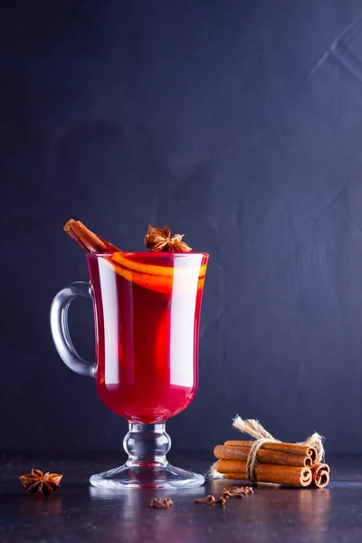 Mulled wine with cinnamon sticks on dark background. Christmas mulled wine with orange, star anise and cinnamon. One glass of mulled wine and spices