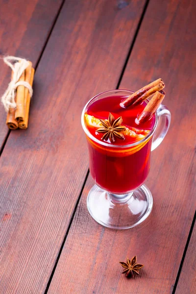 Glass of mulled wine and cinnamon sticks on wooden boards. Christmas mulled wine with orange slices, star anise and cinnamon. One glass of mulled wine and spices