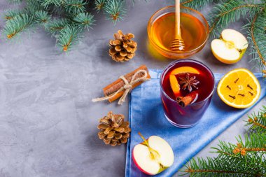 Bardakta baharatlı sıcak şarap. Tarçınlı kırmızı şarap, anason ve bal. Çam kozalaklı, köknar dallı, çimento grisi arka planda sıcak sıcak şarap. Üst görünüm