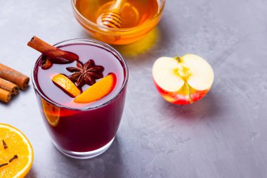Çimento arka planında baharat olan bir bardak sıcak şarap. Noel şarabı, portakal, elma, yıldız anason ve tarçınlı. Kırmızı şarap ve bal gri arka planda. Üst Manzara. Boşluğu kopyala