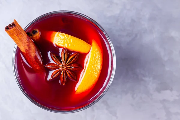 Glass of mulled wine with spices on cement background. Christmas mulled wine with orange, star anise and cinnamon. Red mulled wine on a gray background. Minimalism. Copy space