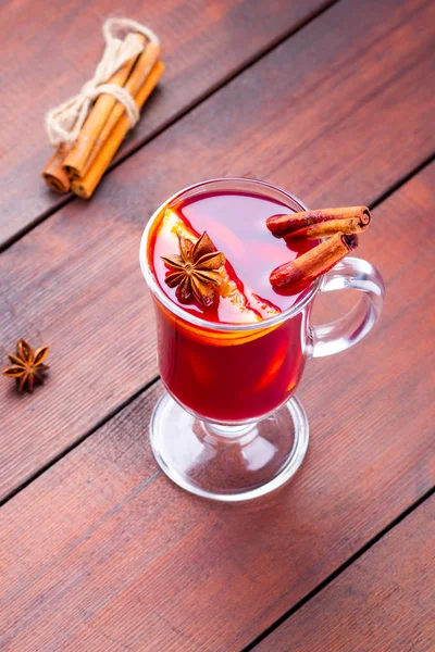 Glass of mulled wine and cinnamon sticks on wooden boards. Christmas mulled wine with orange slices, star anise and cinnamon. One glass of mulled wine and spices