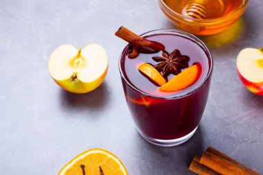 Çimento arka planında baharat olan bir bardak sıcak şarap. Noel şarabı, portakal, elma, yıldız anason ve tarçınlı. Kırmızı şarap ve bal gri arka planda. Üst Manzara. Boşluğu kopyala