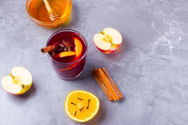 Çimento arka planında baharat olan bir bardak sıcak şarap. Noel şarabı, portakal, elma, yıldız anason ve tarçınlı. Kırmızı şarap ve bal gri arka planda. Üst Manzara. Boşluğu kopyala