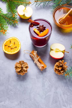 Bardakta baharatlı sıcak şarap. Tarçınlı kırmızı şarap, anason ve bal. Çam kozalakları ve köknar dalları ile çimento gri arka planda sıcak sıcak sıcak şarap