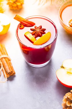 Bardakta baharatlı sıcak şarap. Tarçınlı kırmızı şarap, anason ve bal. Çam kozalakları ve köknar dalları ile çimento gri arka planda sıcak sıcak sıcak şarap